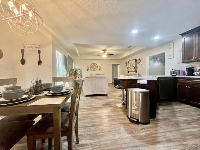 dining room with a tray ceiling, light wood-style floors, recessed lighting, and ceiling fan with notable chandelier