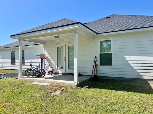 rear view of property featuring a yard, a patio area, and roof with shingles