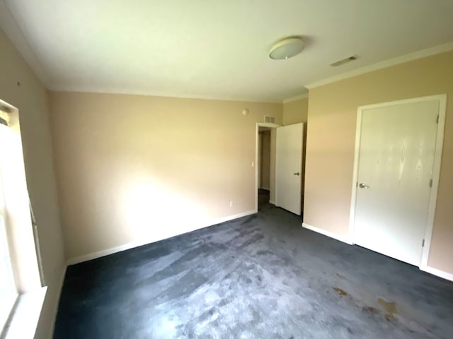 unfurnished bedroom with dark colored carpet and crown molding