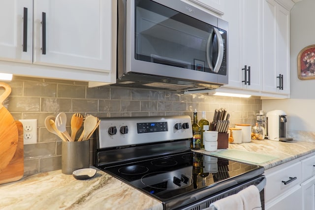 kitchen with light stone counters, decorative backsplash, appliances with stainless steel finishes, and white cabinets