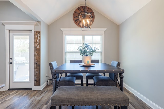 dining room with vaulted ceiling, wood finished floors, baseboards, and a chandelier