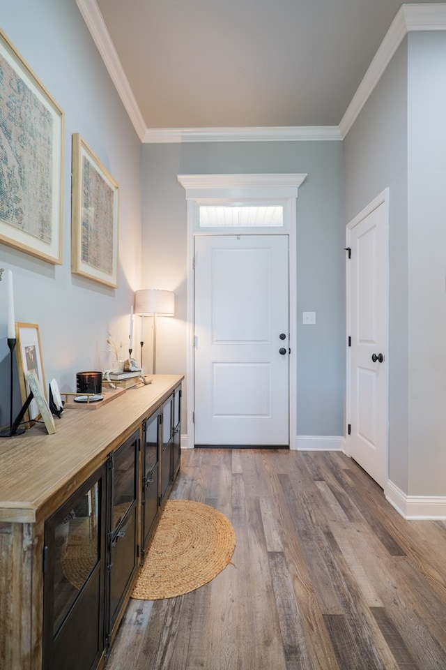 foyer entrance featuring crown molding, baseboards, and wood finished floors