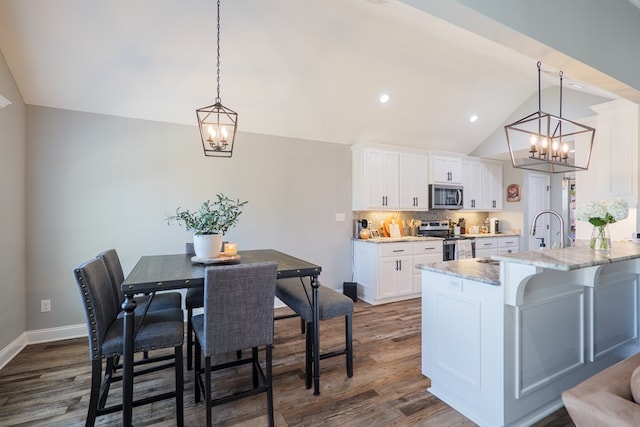 kitchen featuring dark wood-style floors, white cabinets, stainless steel appliances, and vaulted ceiling