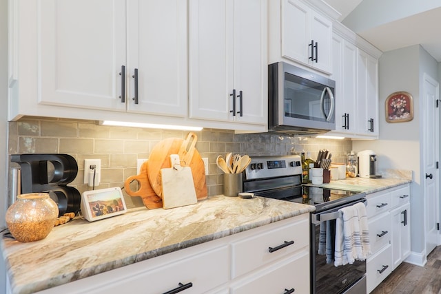 kitchen featuring light stone counters, dark wood-style floors, appliances with stainless steel finishes, white cabinetry, and backsplash