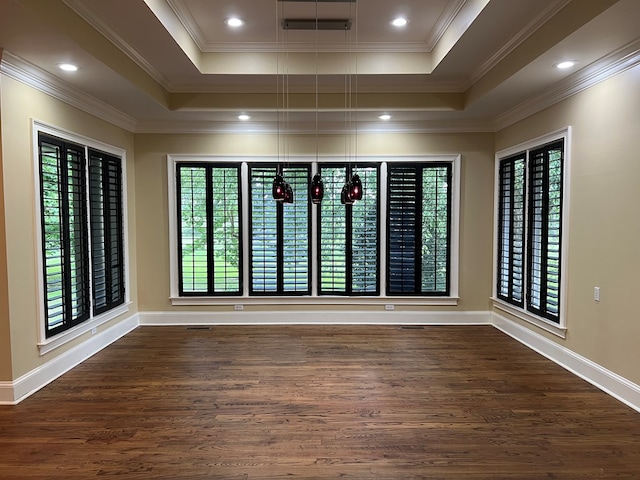 empty room featuring a raised ceiling, dark hardwood / wood-style floors, and ornamental molding