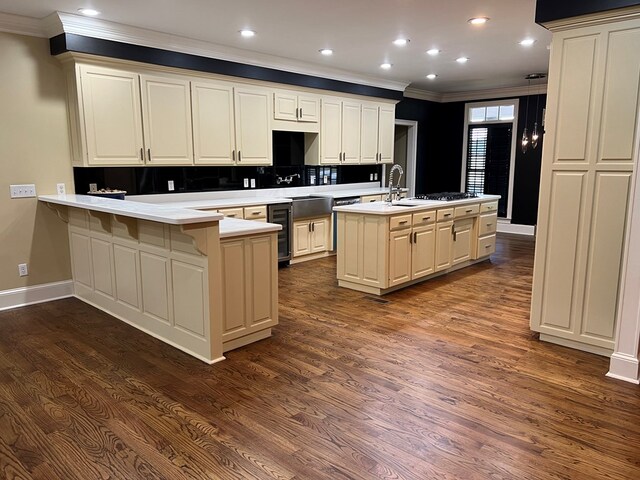 kitchen featuring cream cabinetry, dark hardwood / wood-style flooring, kitchen peninsula, and a kitchen island with sink