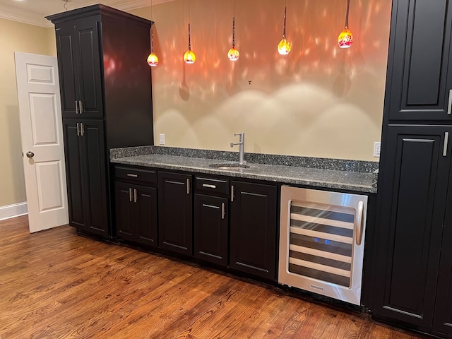 bar featuring dark hardwood / wood-style flooring, beverage cooler, crown molding, sink, and pendant lighting