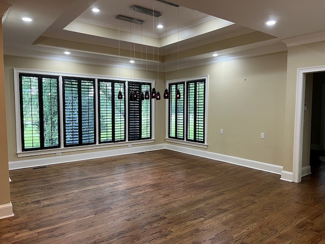 spare room with crown molding, a raised ceiling, and dark wood-type flooring