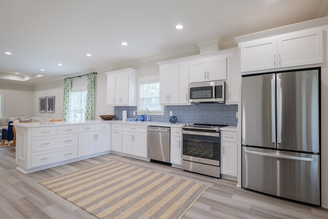 kitchen featuring white cabinets, decorative backsplash, stainless steel appliances, crown molding, and light wood-type flooring