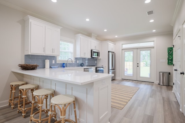 kitchen featuring white cabinetry, sink, stainless steel appliances, and a breakfast bar