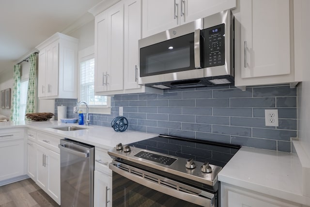 kitchen with appliances with stainless steel finishes, sink, white cabinets, decorative backsplash, and light stone countertops