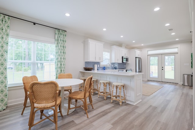 dining area featuring crown molding, sink, french doors, and light hardwood / wood-style flooring