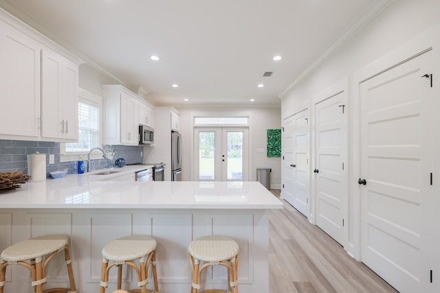 kitchen with white cabinetry, a breakfast bar, stainless steel appliances, and kitchen peninsula