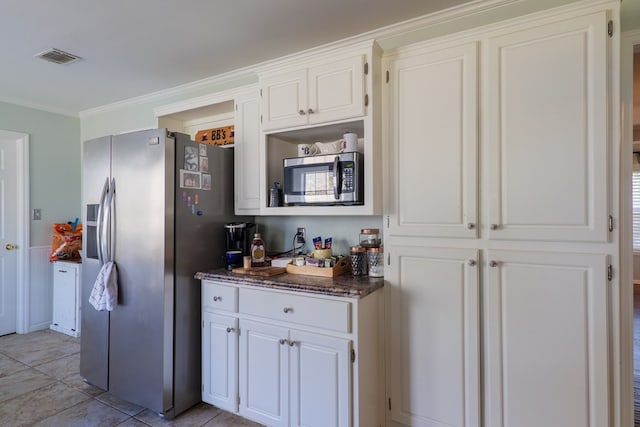 kitchen featuring crown molding, appliances with stainless steel finishes, dark stone countertops, and white cabinets