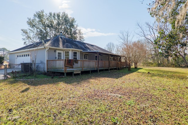 rear view of house featuring a garage, a yard, cooling unit, and a deck