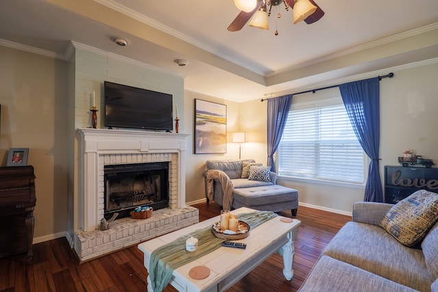 living room featuring a fireplace, dark hardwood / wood-style flooring, ornamental molding, ceiling fan, and a raised ceiling