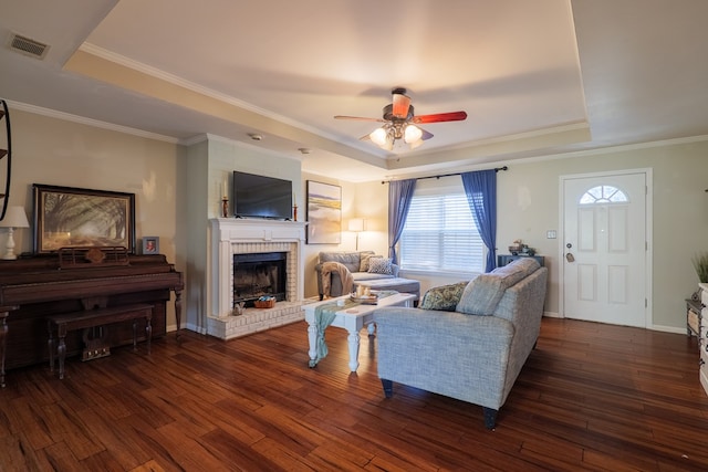 living room featuring a fireplace, dark wood-type flooring, a raised ceiling, and ceiling fan