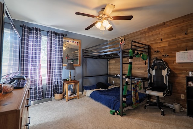 carpeted bedroom with ceiling fan and wood walls