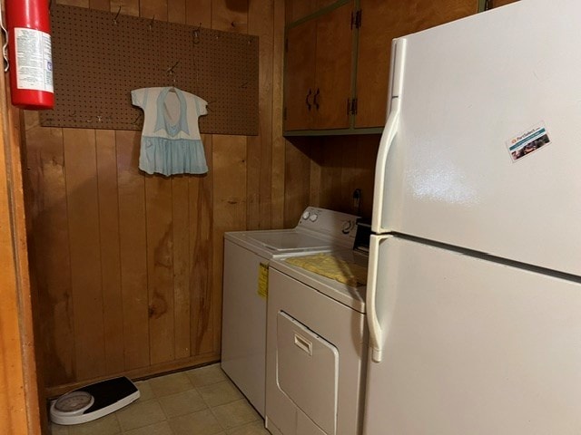 laundry room featuring cabinets, independent washer and dryer, and wood walls