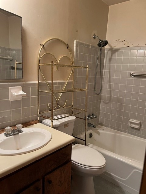 full bathroom featuring vanity, tiled shower / bath, tile patterned flooring, toilet, and tile walls