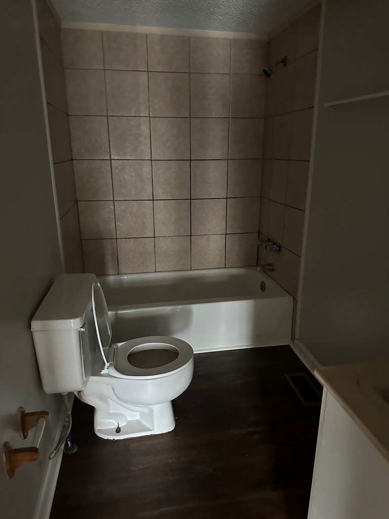 bathroom featuring a textured ceiling, toilet, visible vents, shower / bath combination, and wood finished floors
