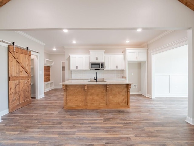 kitchen featuring a barn door, white cabinetry, a center island with sink, and hardwood / wood-style flooring