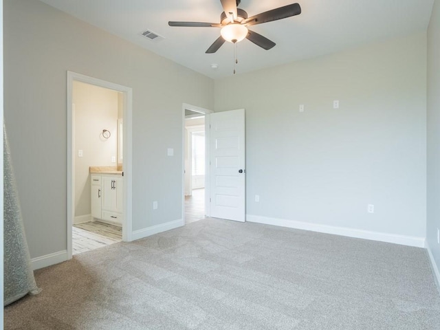 unfurnished bedroom featuring ensuite bath, ceiling fan, and light carpet