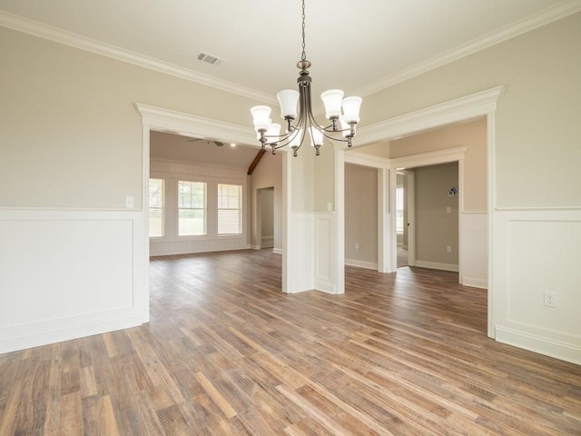 unfurnished dining area featuring hardwood / wood-style floors, crown molding, and an inviting chandelier