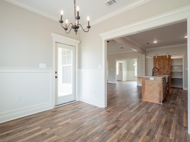 kitchen with hanging light fixtures, an inviting chandelier, dark hardwood / wood-style flooring, a kitchen island with sink, and ornamental molding