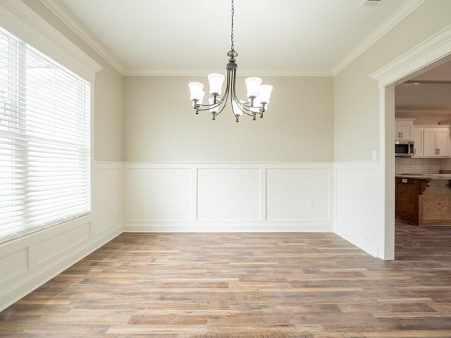 unfurnished dining area with light hardwood / wood-style floors, an inviting chandelier, and ornamental molding