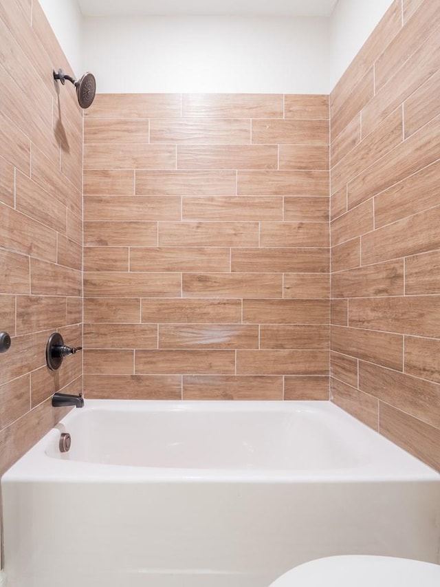 bathroom featuring tiled shower / bath and toilet