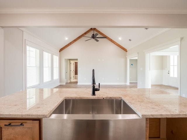 kitchen featuring vaulted ceiling with beams, light stone counters, and sink