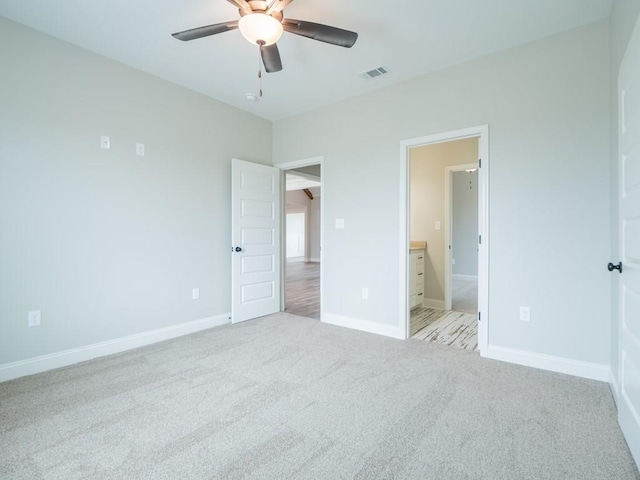 unfurnished bedroom with ensuite bathroom, ceiling fan, and light carpet