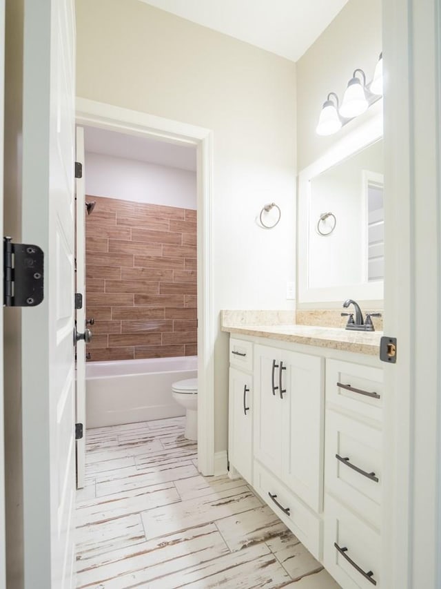 full bathroom featuring vanity, tiled shower / bath combo, and toilet