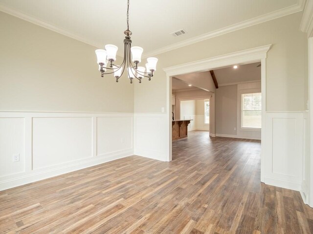 unfurnished dining area with crown molding, hardwood / wood-style floors, and an inviting chandelier