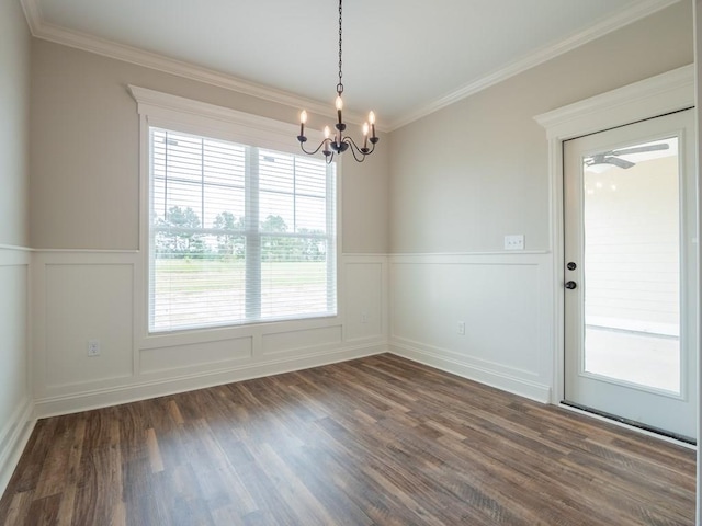 unfurnished dining area featuring dark hardwood / wood-style flooring, ornamental molding, and an inviting chandelier