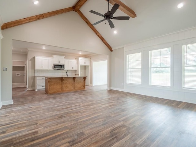 unfurnished living room featuring hardwood / wood-style floors, ceiling fan, beam ceiling, and high vaulted ceiling