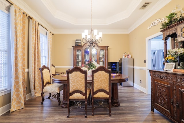 dining space featuring a notable chandelier, dark hardwood / wood-style flooring, and a raised ceiling