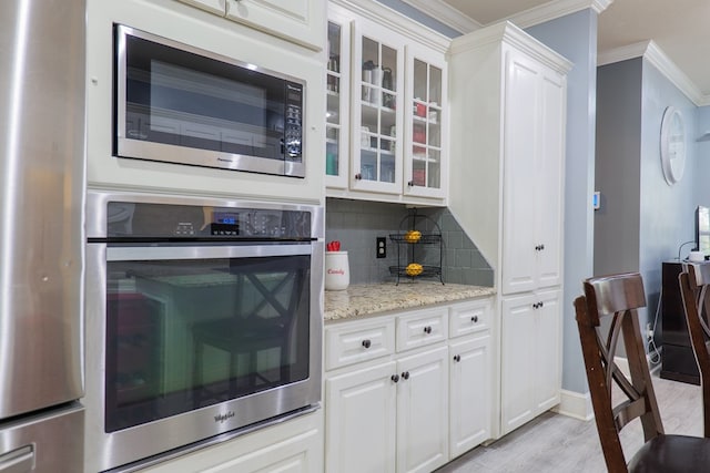 kitchen featuring backsplash, white cabinetry, and stainless steel appliances