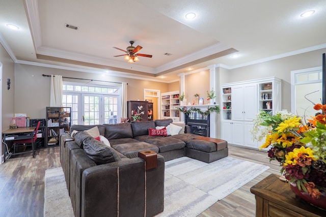 living room featuring a raised ceiling, crown molding, ceiling fan, and hardwood / wood-style flooring