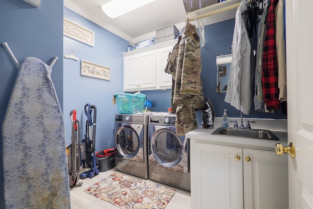 laundry area featuring cabinets, washing machine and dryer, crown molding, and sink