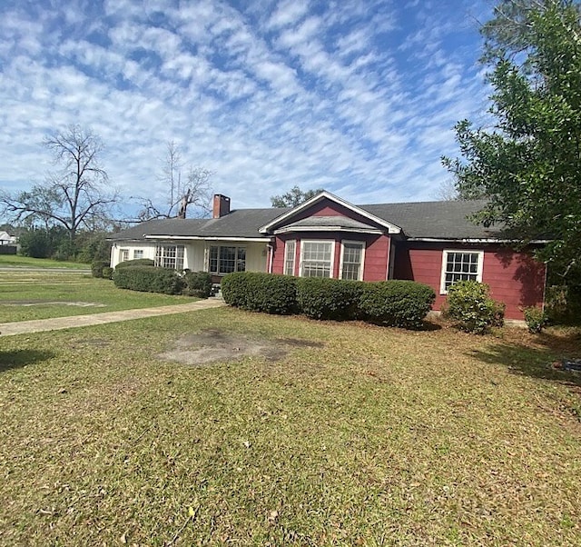 single story home featuring a chimney and a front yard