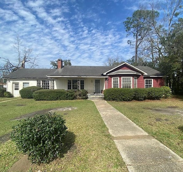 ranch-style house featuring a front lawn and a chimney