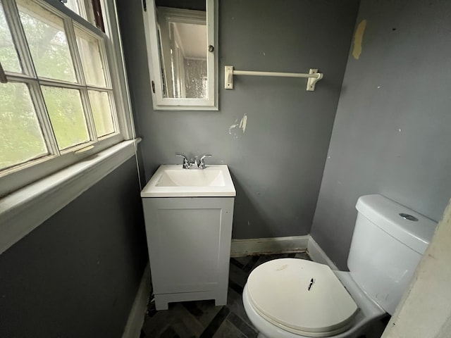 bathroom featuring toilet, baseboards, and vanity