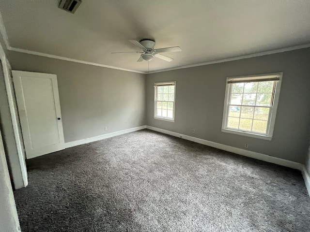 spare room featuring baseboards, dark carpet, visible vents, and crown molding