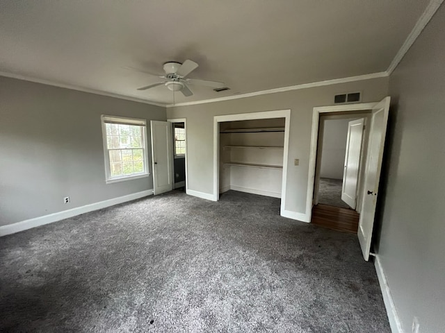 unfurnished bedroom with baseboards, visible vents, dark carpet, and crown molding