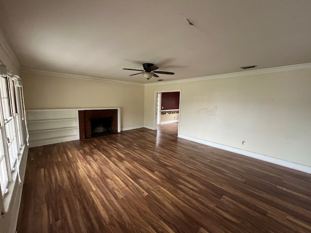 unfurnished living room with crown molding, visible vents, dark wood-type flooring, a brick fireplace, and baseboards