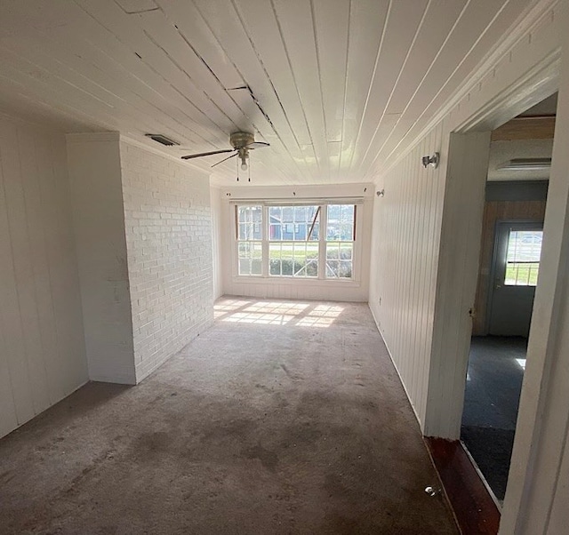 carpeted spare room with a wealth of natural light, wood ceiling, visible vents, and brick wall