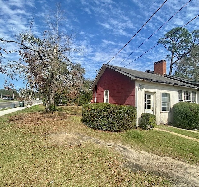 view of side of home featuring a yard and a chimney