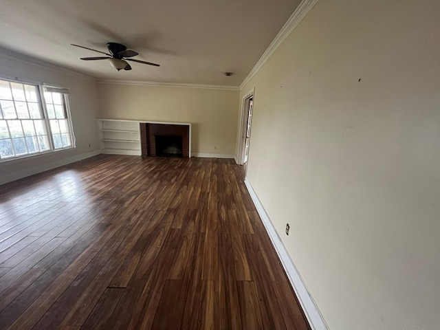 unfurnished living room with dark wood-type flooring, a fireplace, crown molding, and baseboards